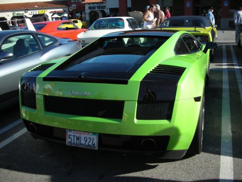 1998 Ford Crown Victoria - green Lamborghini Gallardo with black engine-deck stripe parked rear-first at a busy outdoor car meet.