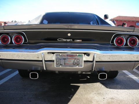 1998 Ford Crown Victoria - Rear view of a dark second-gen Dodge Charger showing Charger script, round taillights and dual exhaust tips.