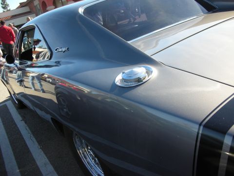1998 Ford Crown Victoria - Detail of a gray Dodge Charger's rear quarter panel showing the Charger badge and a chrome flip-up fuel cap.
