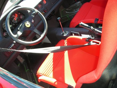 1998 Ford Crown Victoria - stripped-down cockpit of a Ferrari F40 showing red cloth seats, carbon trim and a chrome gated manual shifter.