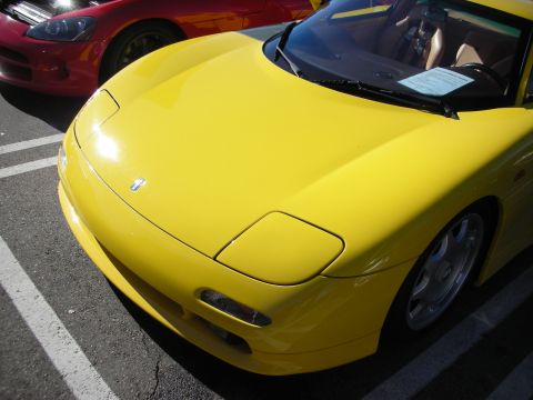 1998 Ford Crown Victoria - Glossy yellow sports car front clip with hideaway headlights parked next to a red sports car at an outdoor event.