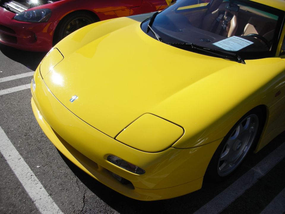 Front end of a yellow sports car parked beside a red sports car