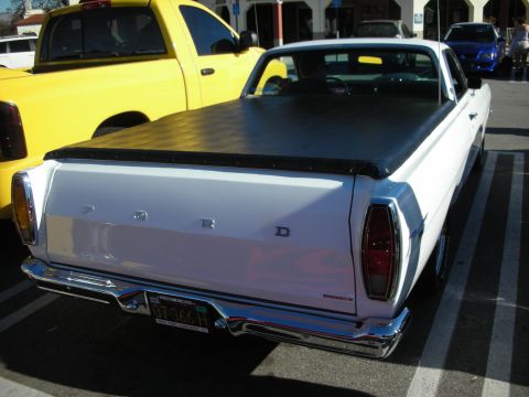 1998 Ford Crown Victoria - White Ford Ranchero rear view showing tailgate FORD lettering, chrome bumper, and a black tonneau cover in a parking lot.