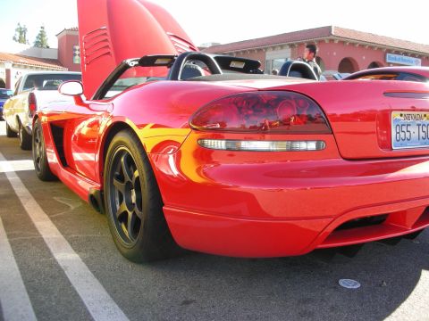 1998 Ford Crown Victoria - Red Dodge Viper convertible rear quarter with black wheels and a Nevada license plate at an outdoor car gathering.