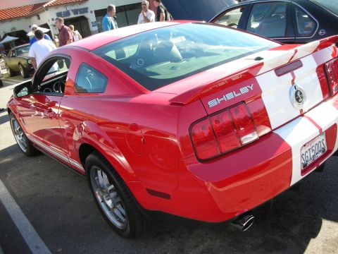 1998 Ford Crown Victoria - Red Shelby Mustang coupe rear three-quarter with white racing stripes, SHELBY decklid badge, and California plate.