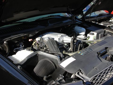 1998 Ford Crown Victoria - Engine bay under an open hood showing a white-cased supercharger, black cone air filter, and a Ford-oval-marked cover.