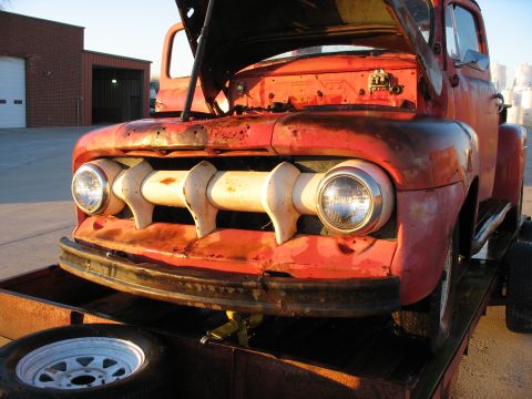 1952 Ford Pickup - The distinctive grille and headlights of a 1952 Ford Pickup are visible as the hood is open, revealing the engine bay.
