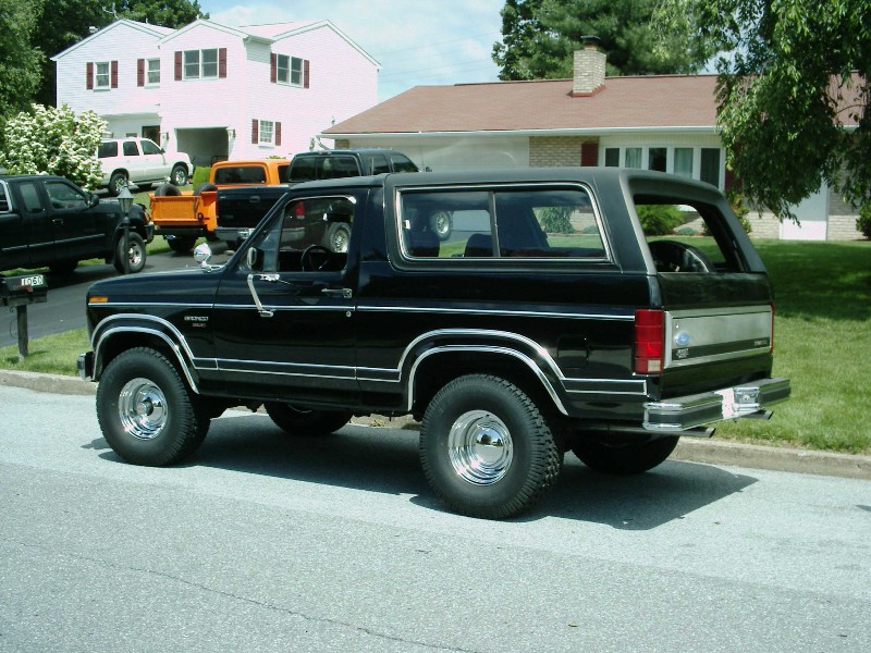 Black Ford Bronco parked on street, other trucks and SUVs in background