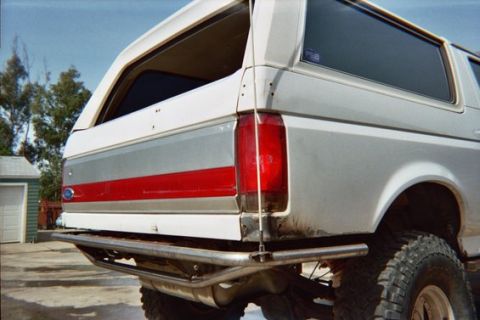 1968 Ford Mustang - Rear view of a white Ford Bronco with a red stripe accent and off-road tires.
