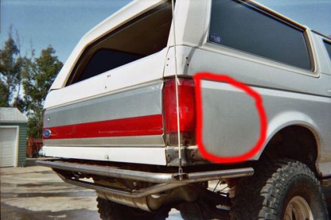 1968 Ford Mustang - Close-up of a dented rear quarter panel on a white Ford Bronco, showing its distinctive trim.