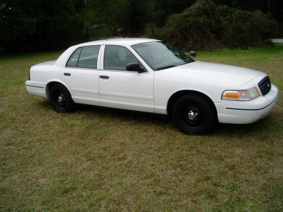 White Ford Crown Victoria sedan with black steel wheels on grass