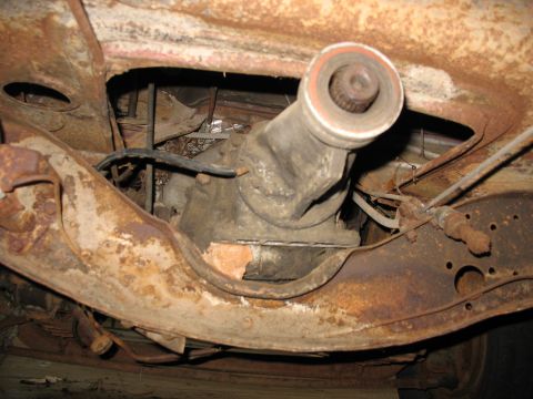 1952 Ford Pickup - The heavily rusted underside of a vehicle reveals its transmission and driveshaft components.