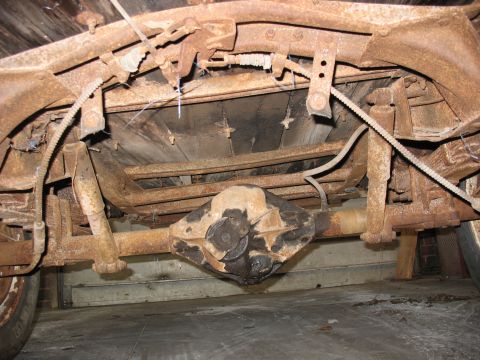 1952 Ford Pickup - The rear axle and frame of a very rusty pickup truck are visible in this undercarriage shot.