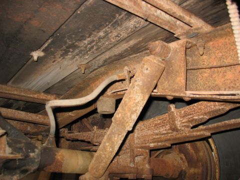 1952 Ford Pickup - The heavily rusted undercarriage of a truck, including suspension components and wooden bed planks, is visible.