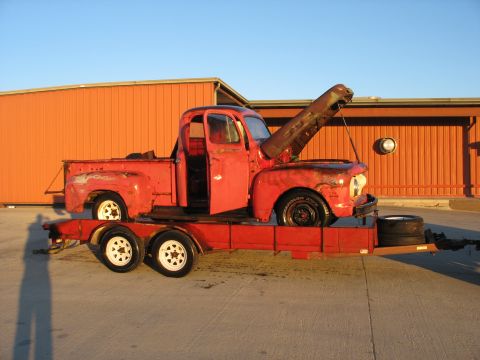 1952 Ford Pickup - A red 1952 Ford Pickup truck is loaded onto a trailer, its hood propped open.