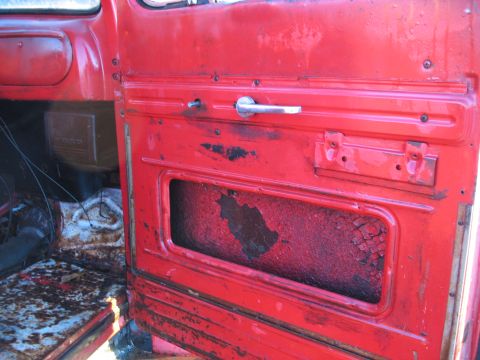 1952 Ford Pickup - Interior view of a 1952 Ford Pickup's red door panel, showing wear and a visible Ford emblem.
