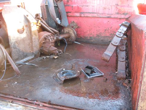 1952 Ford Pickup - Various rusty automotive parts are piled in the bed of a red truck.