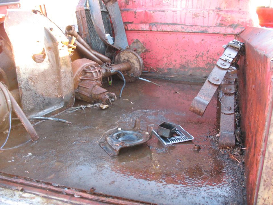 Truck bed filled with rusty parts, including a transmission and differential