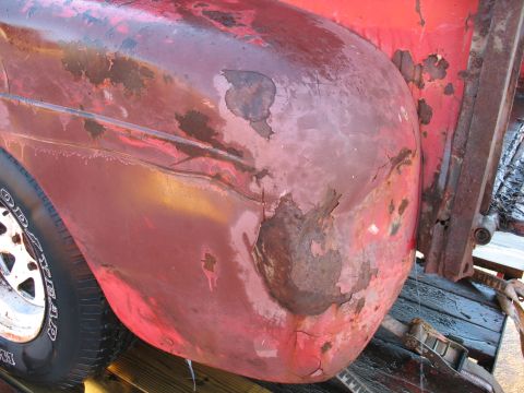 1952 Ford Pickup - The red fender of a 1952 Ford Pickup shows extensive rust and peeling paint, indicating significant wear.