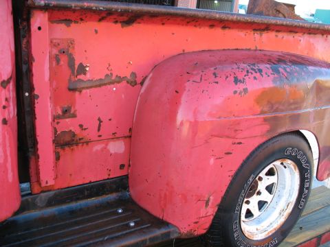 1952 Ford Pickup - Detail of a 1952 Ford Pickup's red bed and fender, showing wear and tear.