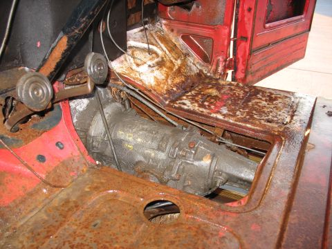 1952 Ford Pickup - The interior of a vintage truck shows significant rust on the floorboards and transmission tunnel.