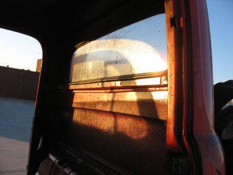 1952 Ford Pickup - Sunset light streams through the cracked rear window of a 1952 Ford Pickup's interior.