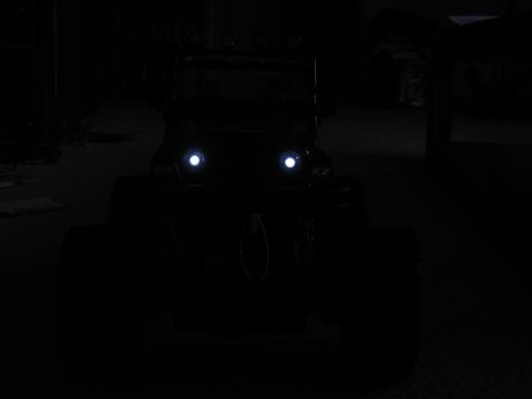 1990 Ford Bronco - Front view of an off-road vehicle at night, its headlights illuminated.