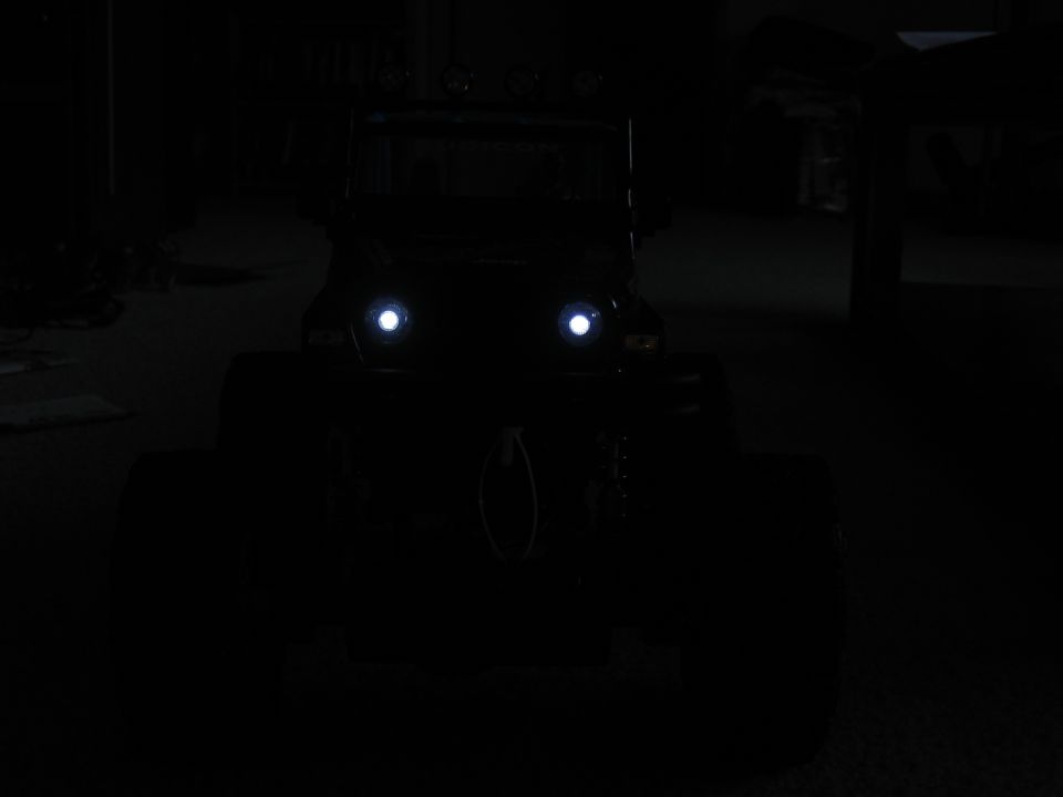 Off-road vehicle with bright headlights on, front view in darkness