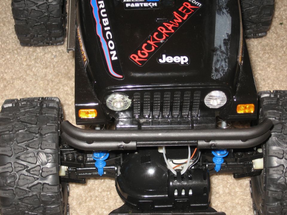 Black Jeep Wrangler Rubicon with "Rockcrawler" decal, front view. Visible details include grille, headlights, bumper, and large tires
