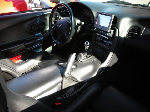 1998 Ford Crown Victoria - Black leather Corvette interior showing a manual gear shifter, steering wheel, and a center dash-mounted screen.