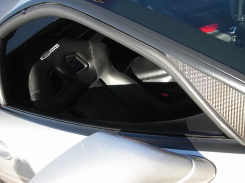 1998 Ford Crown Victoria - View through a side window of a black sport seat with a Z06 logo and carbon-fiber trim panel in a sports car.