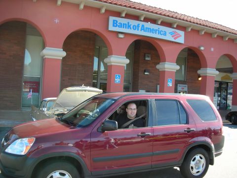 1998 Ford Crown Victoria - man sits in the driver seat of a maroon Honda CR-V SUV parked in front of a Bank of America storefront.