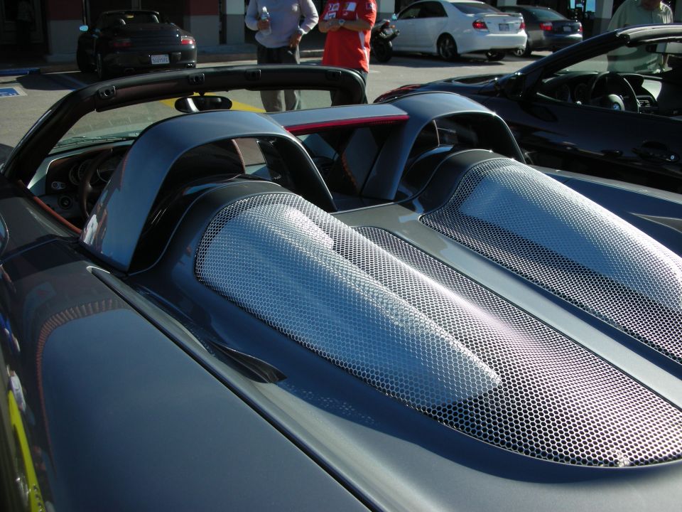 Rear deck and engine cover vents of a dark open-top mid-engine sports car at a car show