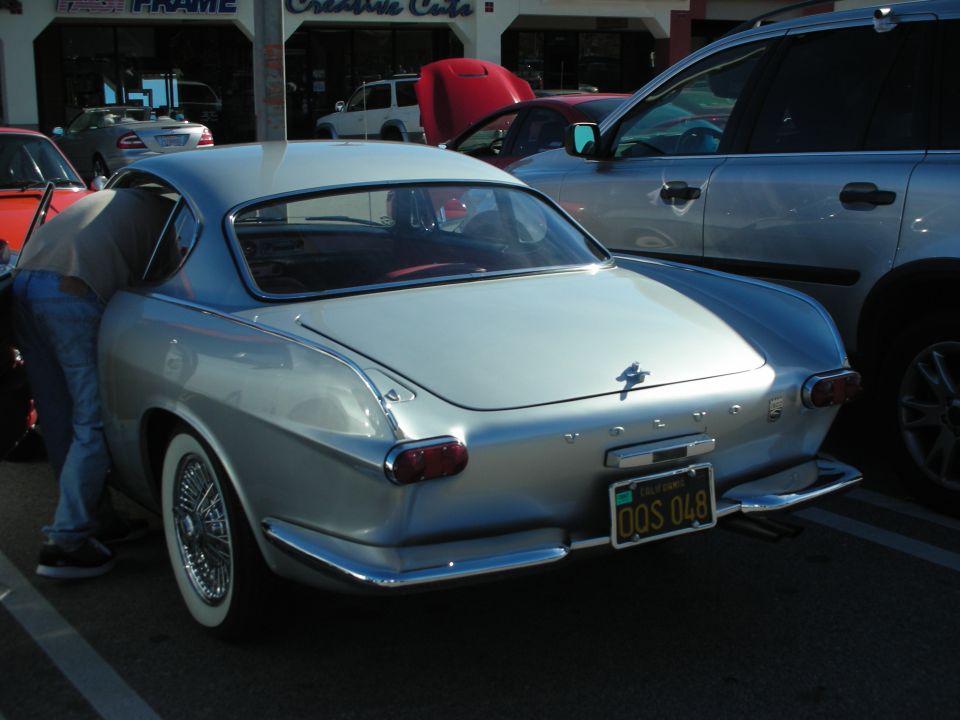 Silver Volvo P1800 coupe rear three-quarter with wire wheels and yellow California plate