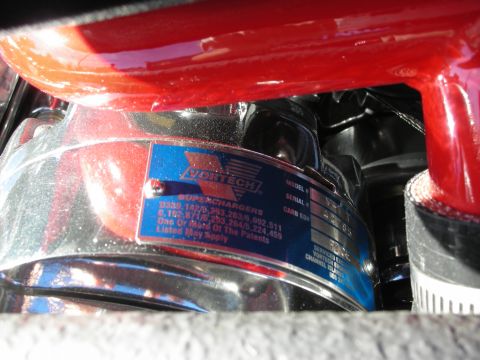 1998 Ford Crown Victoria - Macro view of a blue Vortech Superchargers info plate riveted to a chromed engine part with a red painted surface above.