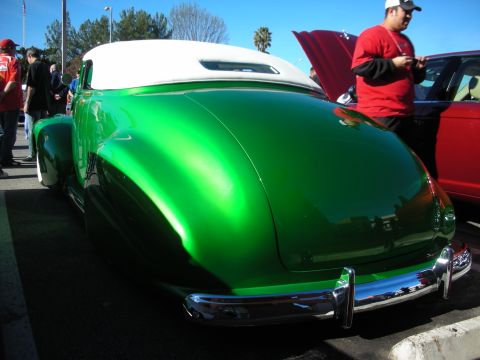 1998 Ford Crown Victoria - glossy candy-green chopped custom coupe with a white folding top and chrome bumper sits parked at an outdoor car show.