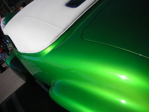 1998 Ford Crown Victoria - Extreme close-up of the candy-green metallic body and white top of a custom car, showing deep paint reflections.