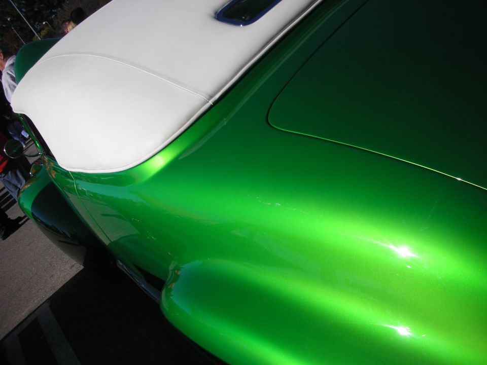 Close-up of a green metallic fender curving up to a white convertible top