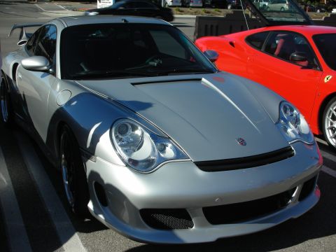 1998 Ford Crown Victoria - silver Porsche 911 with aftermarket bumper and headlights sits next to a red Ferrari in a parking lot.