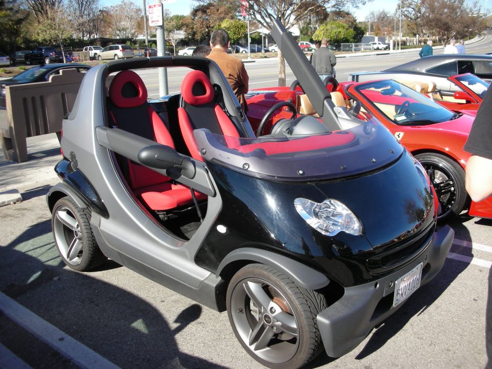 Black and silver Smart roadster with red interior at a car show