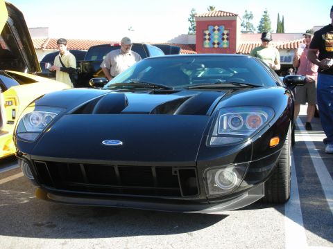 1998 Ford Crown Victoria - Head-on view of a black Ford GT showing its quad headlights, hood vents and Ford oval badge, surrounded by spectators.