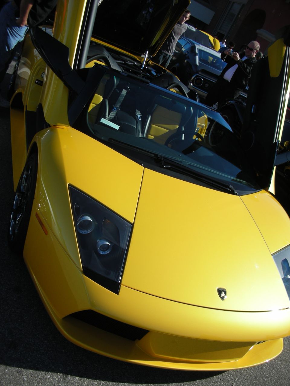 Front of a yellow Lamborghini Murcielago with raised door at a meet
