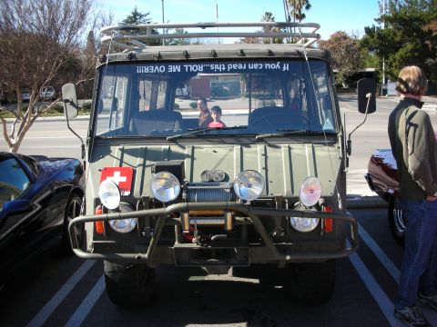 1998 Ford Crown Victoria - olive-drab military-style off-road truck with brush guard, winch, auxiliary lights and a humorous windshield decal.