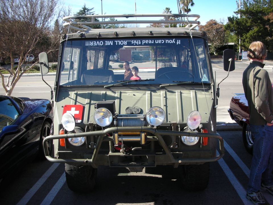 Front of an olive-green Pinzgauer-style military 6x6 with brush guard and lights
