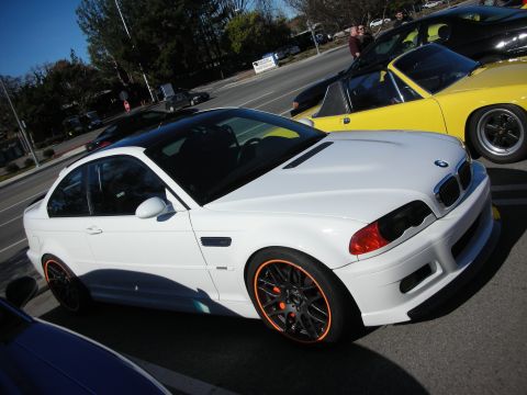 1998 Ford Crown Victoria - Side view of a white BMW M3 coupe on orange-and-black wheels with red calipers, parked next to a yellow car.