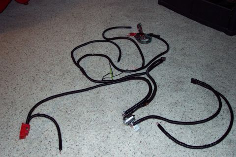1991 Ford Bronco - A complex vehicle wiring harness is spread across a carpeted floor, showing its various connectors and components.