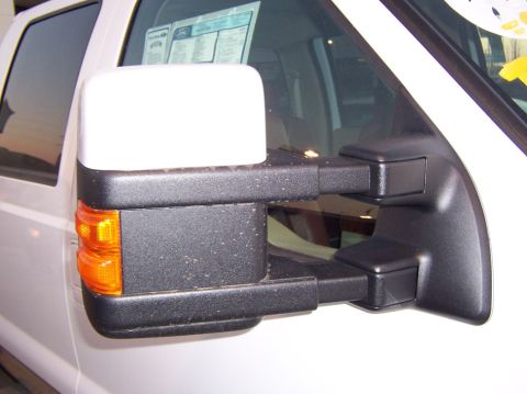2000 Ford Excursion - A close-up view of a white truck's side mirror assembly, showing details of its construction and an interior window sticker.