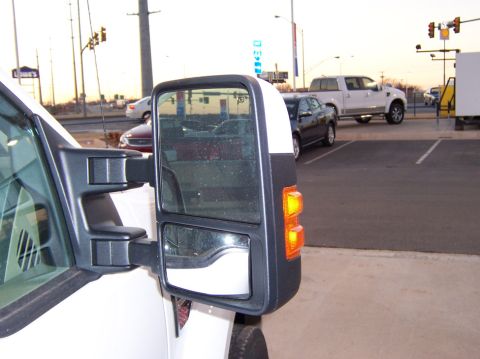 2000 Ford Excursion - Close-up of a white truck's side mirror, showing the turn signal and reflection of other vehicles in the parking lot.