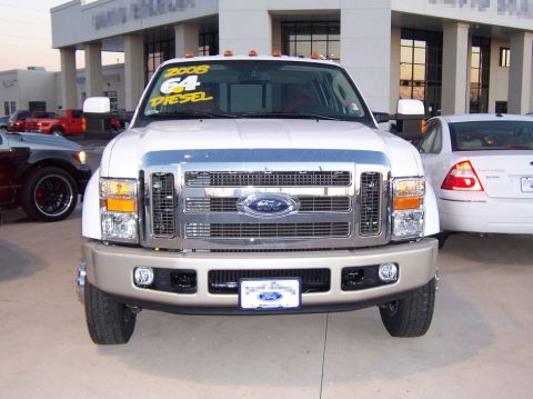 2000 Ford Excursion - White 2008 Ford Super Duty truck parked in front of a building with another car nearby.