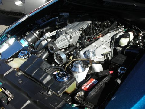 1998 Ford Crown Victoria - detailed supercharged V8 engine sits in the polished engine bay of a teal-green car at a show.